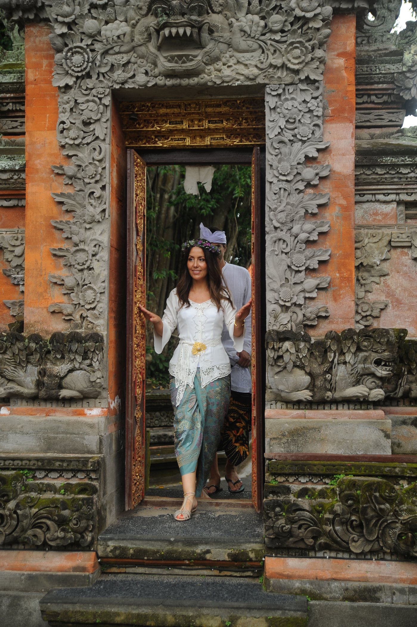 Novia con traje balinés y corona de flores cruzando la puerta de un templo de Ubud el día de su boda balinesa
