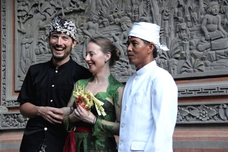 Pareja vestida con trajes balineses junto al sacerdote tras la bendición de su boda balinesa