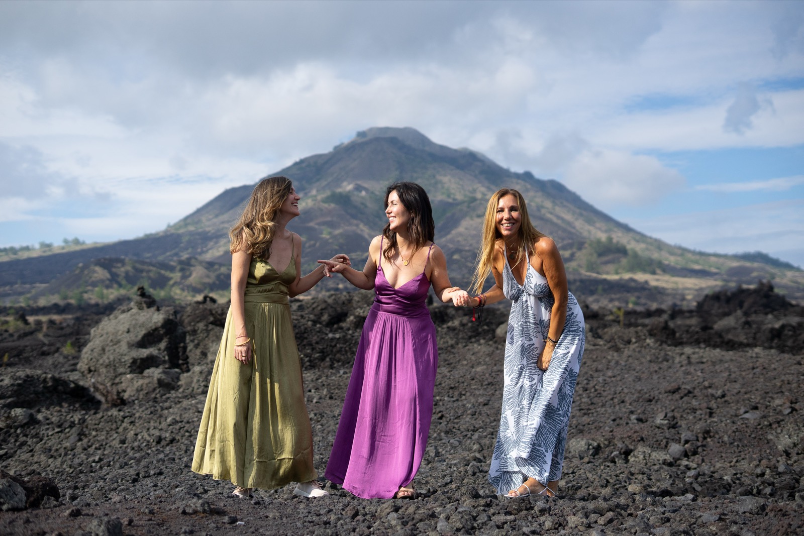 Tres viajeras riendo abrazadas frente al volcán Batur, Bali